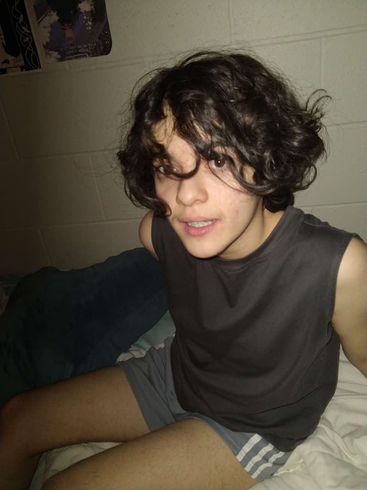 Alba is sitting on his dorm bed, in the middle of a movement. The camera flash gives him a surprised expression.